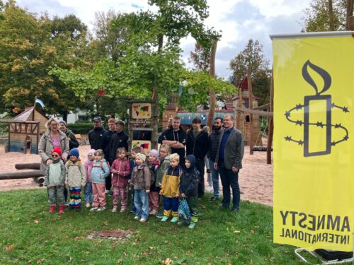 Kindergartenkinder des Paul-Gerhardt-Kindergarten in Kulmbach unter der Leitung von Monika Hoffmann, Schüler*innen der 12. Klasse der Maurer*innen und Betonbauer*innen der UNESCO-Projektschule Berufliches Schulzentrum Kulmbach, 3. Bürgermeister Dr. Ralf Hartnack (ganz rechts im Bild) vor dem Baum der Menschenrechte in Kulmbach (am Spielplatz Ruster Garten)